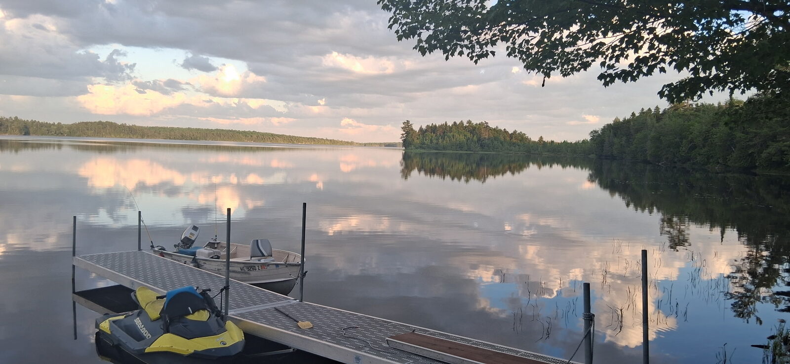 Fishing boat and jet ski at the camp dock on a calm evening